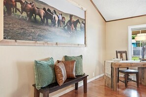A room with a wooden bench, a table, and a large painting of horses. - Long Live Cowboys!  3-Bed 2-Bath Near ACU and Expo (Abilene)