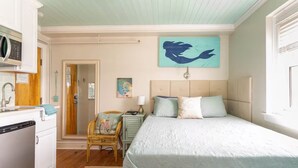 Un dormitorio con cama, una silla, un escritorio y un cuadro en la pared.