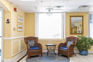 A room with two wicker chairs, a small table, a potted plant, a chandelier, and a large mirror. - Cozy 1-bedroom condo in marvelous Ocean City with AC - half a block to Beach!!! (Ocean City)