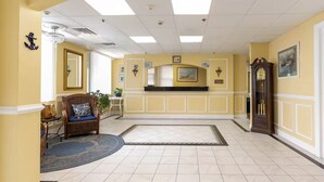 Un vestíbulo de hotel con mostrador de recepción, un espejo grande, un reloj y un candelabro.