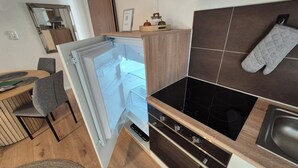Une cuisine compacte équipée d’un réfrigérateur encastré, d’une cuisinière et d’un four à micro-ondes.