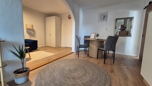Un salon moderne avec un canapé, une table à manger et des chaises, un grand miroir et une plante en pot.