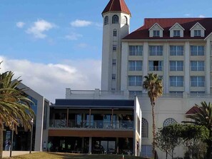 A hotel with a prominent tower, a large building with multiple windows, and a covered area with outdoor seating. - Cosy & Tranquil Family Beach Getaway (Gqeberha)
