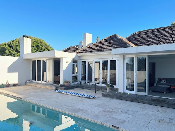 Una casa moderna con piscina, grandes puertas de cristal y un área de patio.