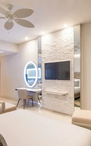 A modern bedroom with a bed, a desk, a chair, a TV mounted on a textured wall, and a ceiling fan.