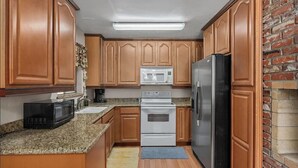 A kitchen with wooden cabinets, a stainless steel refrigerator, a microwave, and an oven. - Riverkern Retreat House (Kernville)
