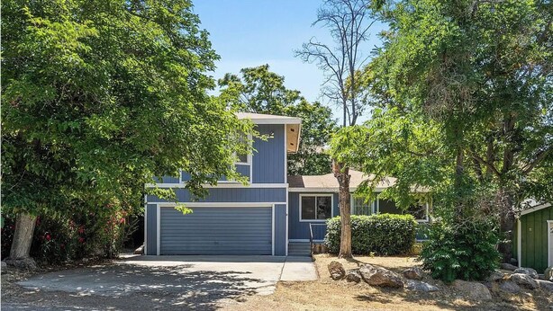 A modern two-story house with a garage, surrounded by trees and a well-maintained lawn. - Riverkern Retreat House (Kernville)