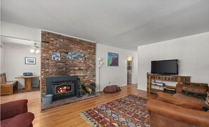 Una sala de estar con chimenea de ladrillo, televisor y alfombra estampada.