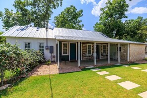 A single-story house with a covered porch, a stone extension, and a well-maintained lawn. - Pool&Hot Tub | Large Yard | Walk2Main | Fire Pit (Fredericksburg)