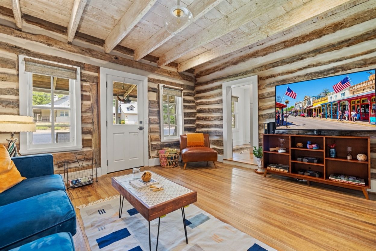 A log cabin interior with a TV, sofa, coffee table, and a bookshelf.
