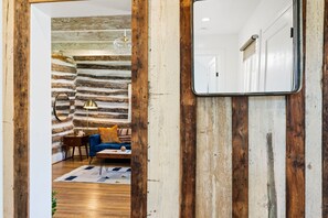 Ein Zimmer mit rustikaler Steinwand, einem blauen Sofa, Holzboden und einem Spiegel an der Wand.