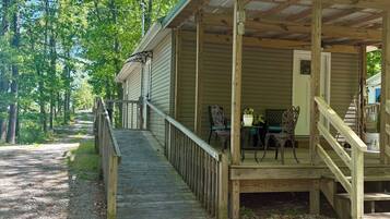A wooden cabin with a porch, a table with chairs, and a gravel path leading to it.