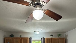 Eine Küche mit Holzausstattung, einem weißen Kühlschrank, einer Spüle, einem Herd und einem Deckenventilator.
