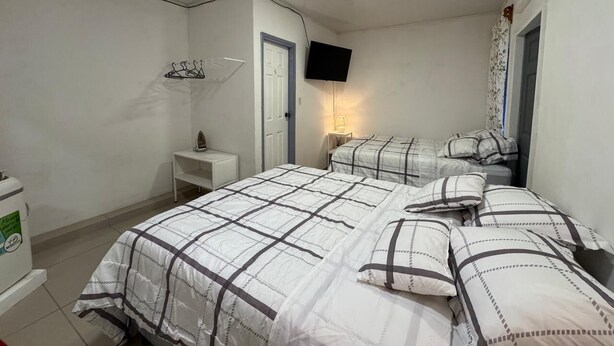 Ein Schlafzimmer mit zwei Betten, einem Fernseher, einem kleinen Nachttisch und einem an der Wand befestigten Regal.