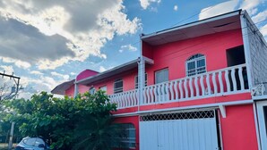 Ein rotes Gebäude mit einem weißen Balkon, einer Garage und einem geparkten Auto.