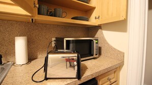 A kitchen with a toaster, microwave, and wooden cabinets.