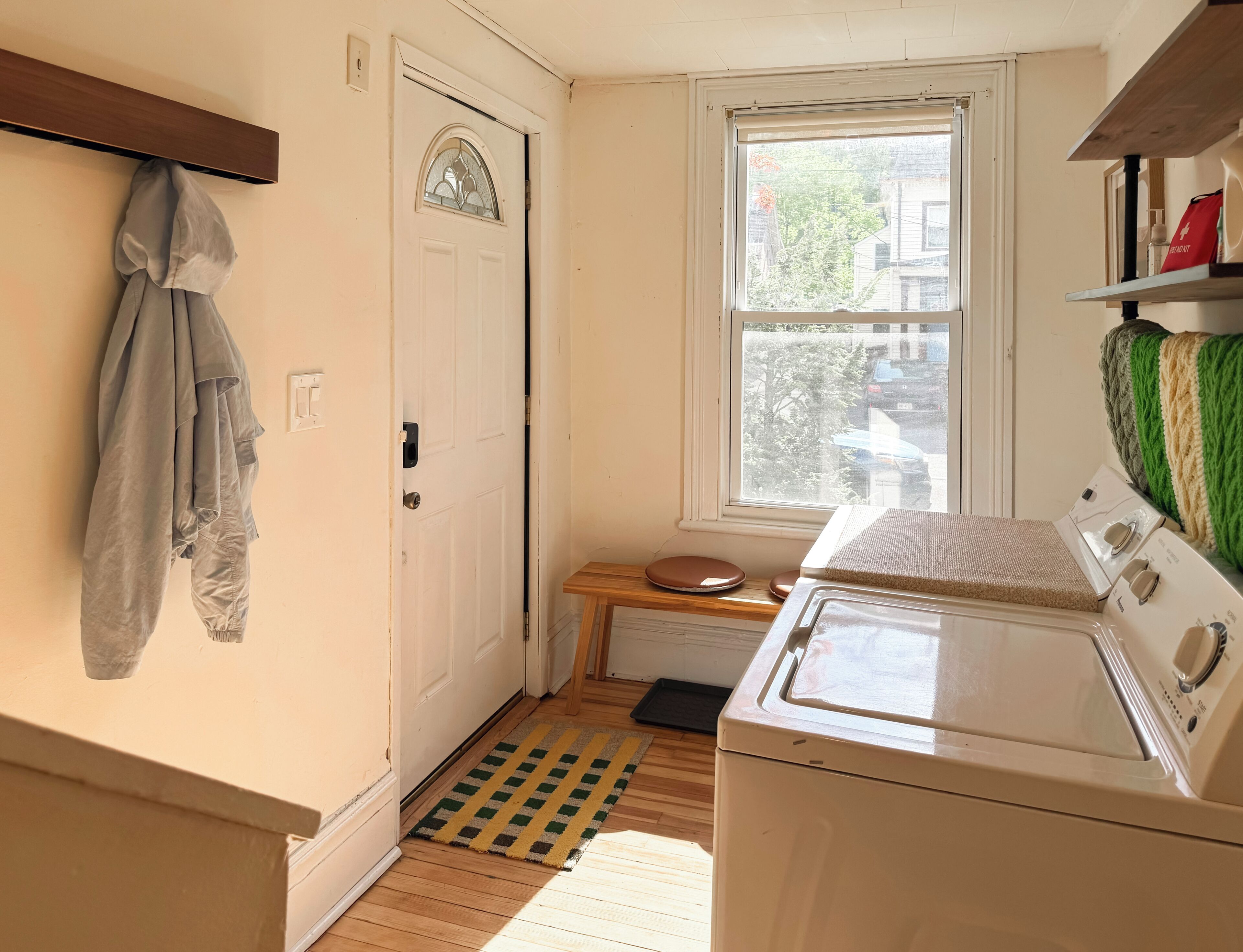 Une buanderie équipée d’un lave-linge, d’une porte avec une fenêtre et d’un porte-manteau.