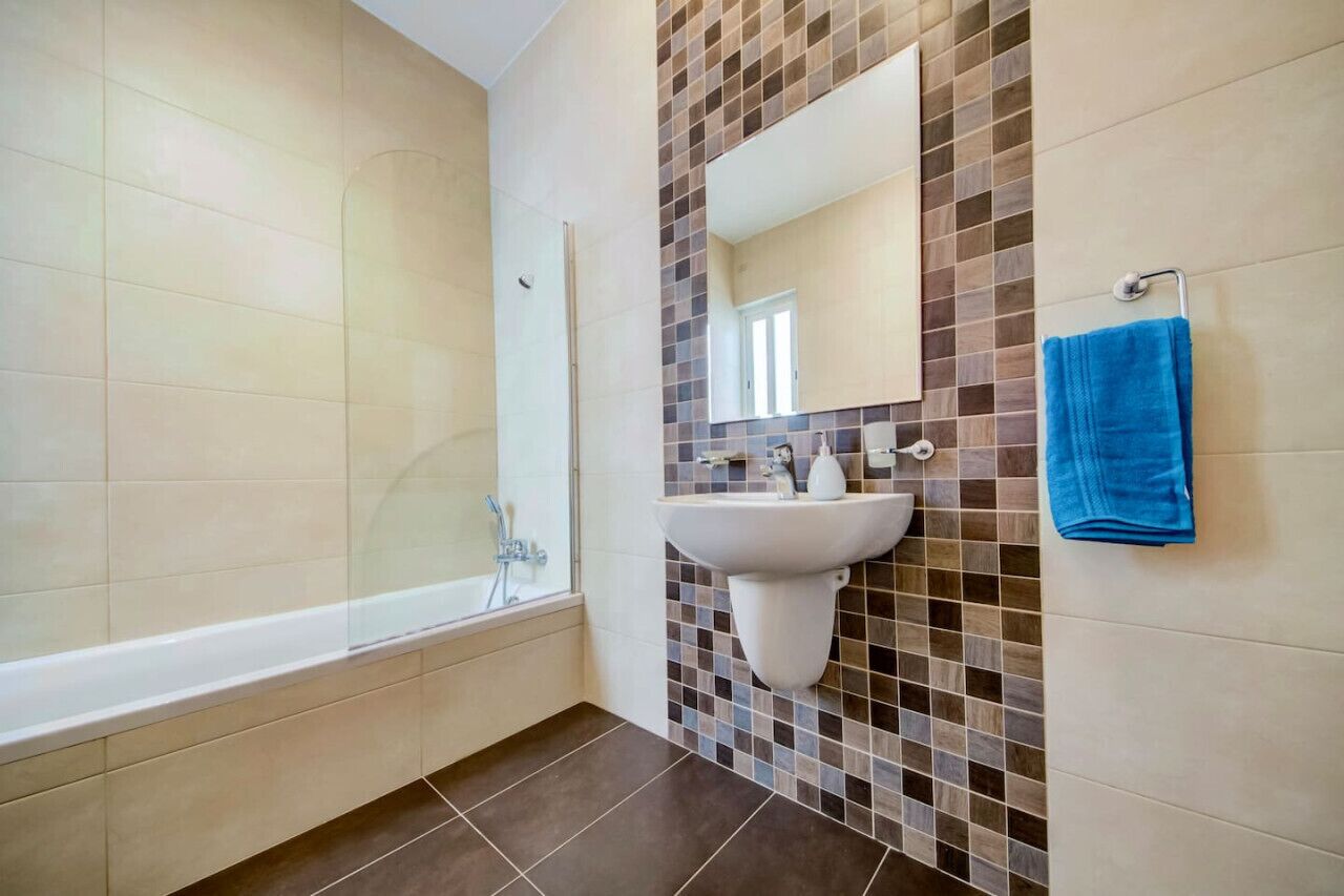 Uma casa de banho com uma banheira, uma pia, um espelho e uma toalha azul.