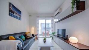 Un salon moderne avec un canapé, une table basse, un téléviseur et un balcon offrant une vue agréable.