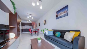 Un salon moderne comprenant un canapé, une table basse, un téléviseur et un coin repas avec des chaises et une table.