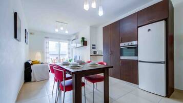 A modern kitchen with a dining table, chairs, and a refrigerator.
