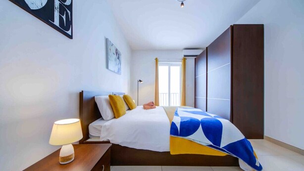 Une chambre d’hôtel avec un lit, une table de chevet, une lampe, un tableau au mur et une armoire.