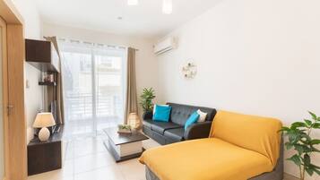 Une chambre moderne avec un canapé, un lit, une table basse, une lampe, une plante et une vue par la fenêtre.