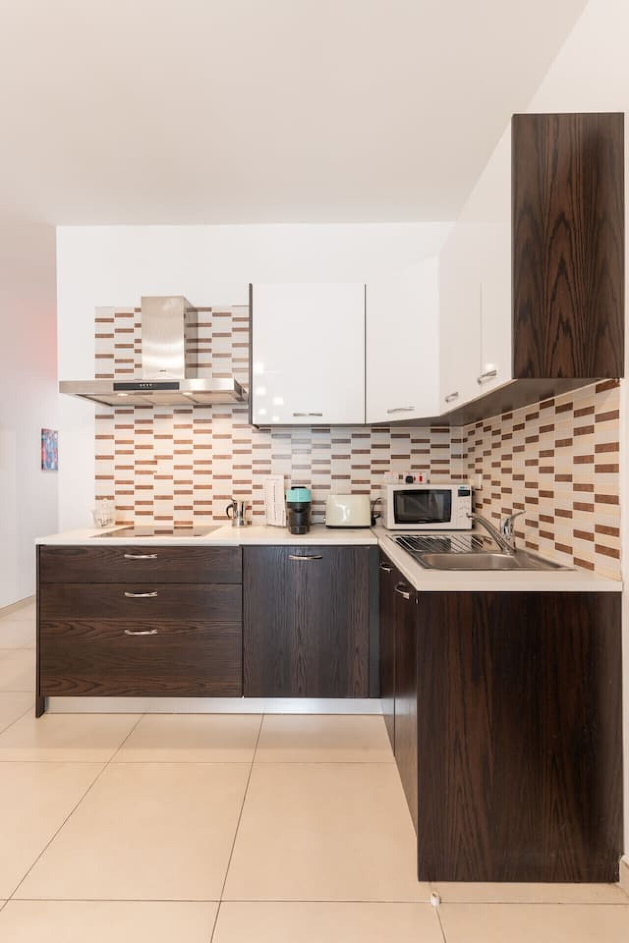 A modern kitchen with a central island, dark wood cabinets, a microwave, and a coffee maker.