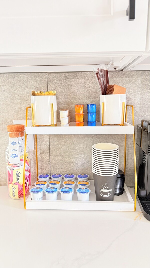 Una encimera de cocina con espacio para café, que incluye tazas, azúcar y una cafetera.