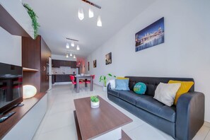 Ein modernes Wohnzimmer mit Sofa, Couchtisch, Fernseher und Essbereich.