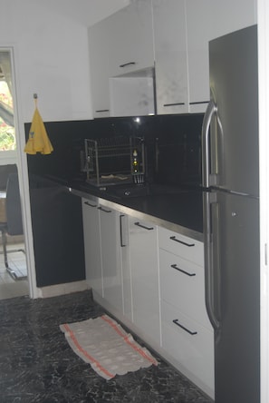 Eine Küche mit Kühlschrank, Mikrowelle und einem gelben Stoff an der Tür.