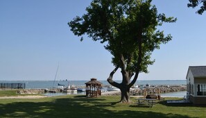 A tree, a gazebo, a swing set, and a building by a waterfront. - Beach View 2BR Cottage #3 at South Beach Resort (Lakeside Marblehead)