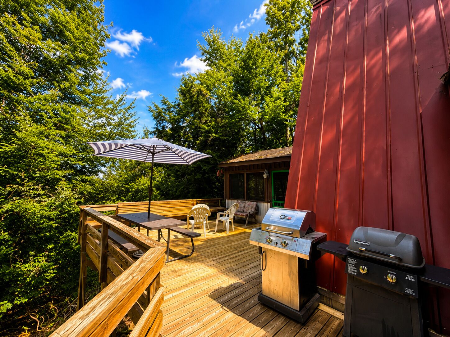 A wooden deck with a grill station, a table with chairs, and an umbrella.