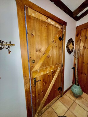 Eine Holztür mit einem Metallgriff und einer dekorativen Metallverkleidung an der Wand.