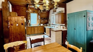 A wooden interior with a dining table, chairs, a kitchen area, and a blue cabinet. - Rustic Pine Lodge - Cozy 4 BR Adirondack Escape (Schroon Lake)