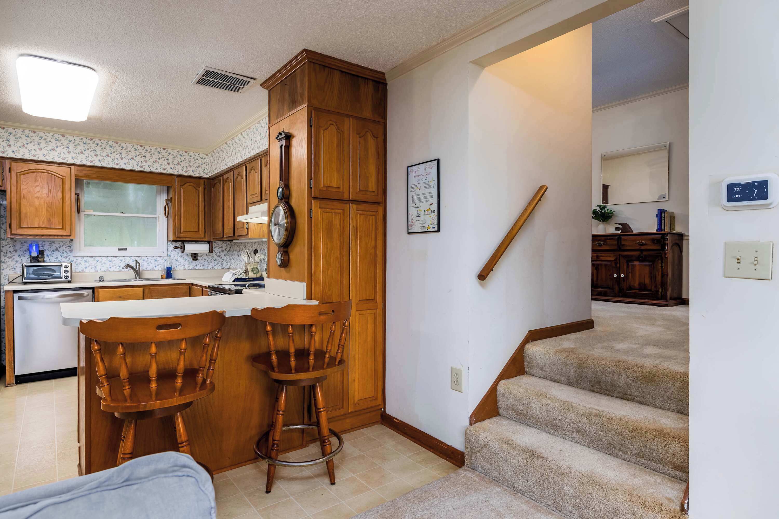 A kitchen with wooden cabinets, a double sink, and a bar stool.