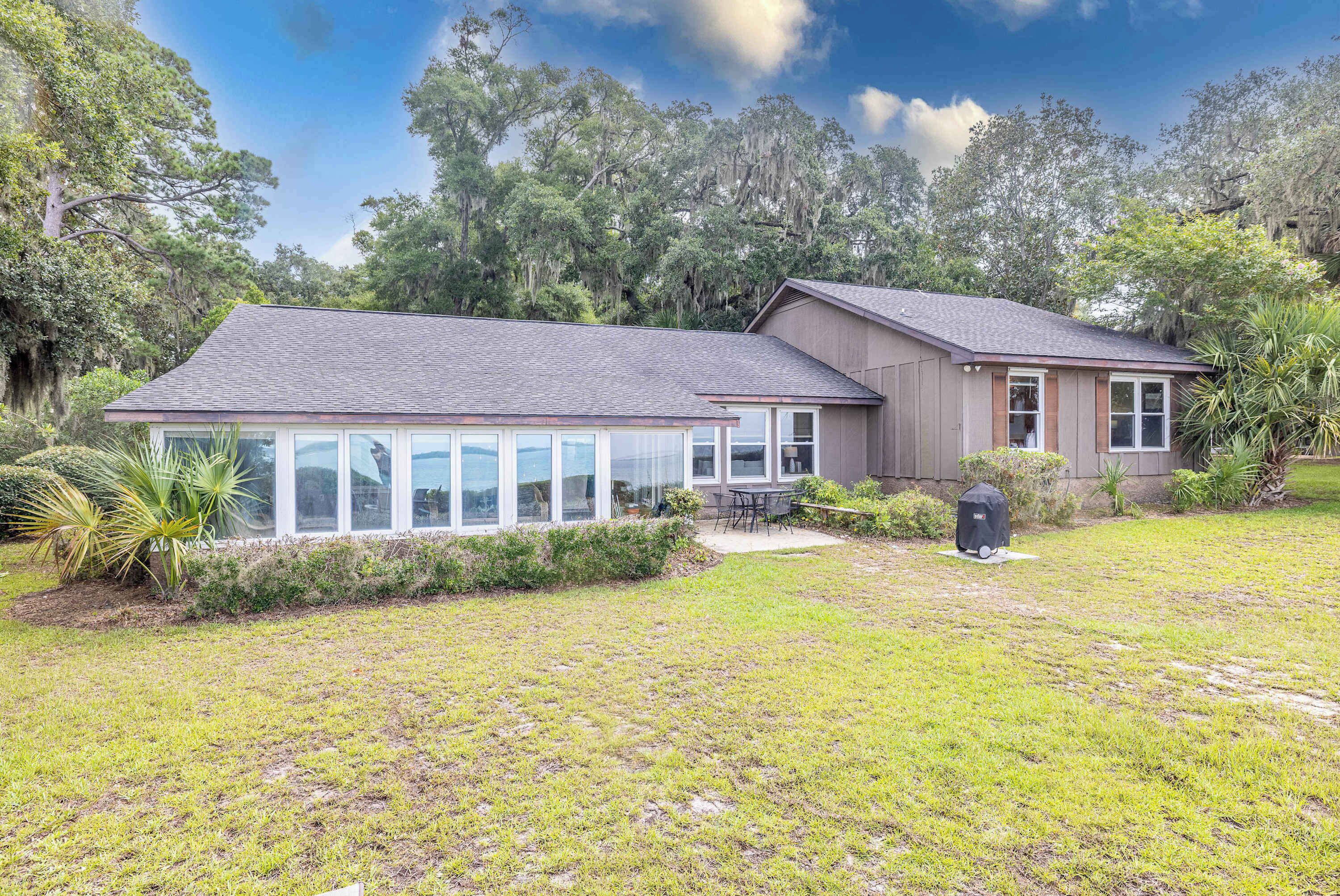A house with a large glass enclosure, a covered patio, and a well-maintained lawn.