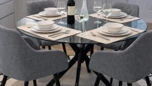 Een moderne keuken met een eettafel voor vier personen, een wijnfles en een potplant.