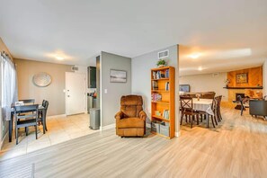 Ein Wohnzimmer mit Sofa, eine Essecke mit Tisch und Stühlen, ein Küchenbereich mit Kühlschrank und ein Kamin.