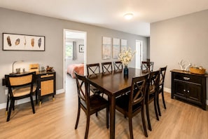 A dining area with a wooden table and chairs, a buffet station, and a wall-mounted artwork of feathers. - 5BR San Diego Retreat | Hot Tub, Private Yard, AC (Spring Valley)