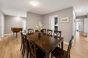 Ein Essbereich mit einem großen Holztisch, sechs Stühlen und einem Blumenstrauß.