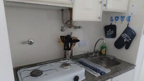 Een keuken met een gasfornuis, een spoelbak en een afwasschaal.