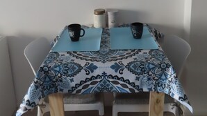 Een eettafel met twee zwarte mokken, een tafelkleed met dessin en twee placemats.