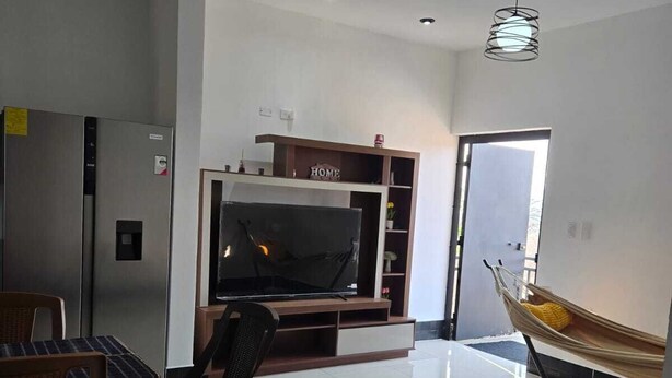 Un soggiorno moderno con una TV a schermo piatto, un'area pranzo con sedie, un divano e un'amaca.