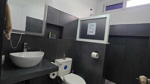 Un bagno moderno con un ampio lavandino bianco, un water e uno specchio.