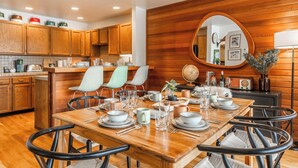 Une cuisine moderne avec des meubles en bois, une table à manger pour quatre personnes et un grand miroir rond accroché au mur.