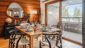 Un coin repas avec une table en bois dressée pour quatre personnes, entourée de quatre chaises, d’un miroir et d’une cheminée.