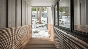 Un couloir doté d’un plancher en bois, de rampes en métal et de grandes fenêtres donnant sur un espace extérieur enneigé.