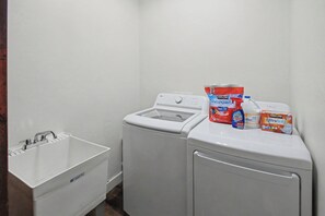 A laundry area with a washing machine, a dryer, and various detergent bottles. - NEW 3-bedroom 2-bath house in marvelous Lake of the Woods with central AC (Lake of the Woods)