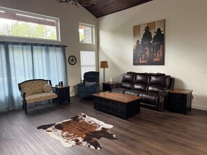 A living room with a leather sofa, a patterned armchair, a wooden coffee table, and a cowhide rug. - NEW 3-bedroom 2-bath house in marvelous Lake of the Woods with central AC (Lake of the Woods)